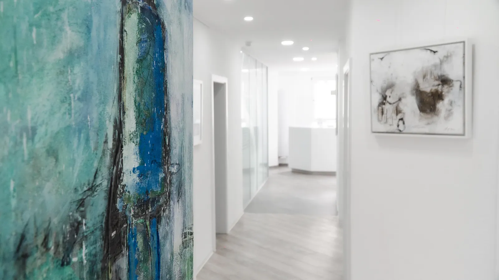 Heller Flur der Praxis mit Kunstwerken an den Wänden